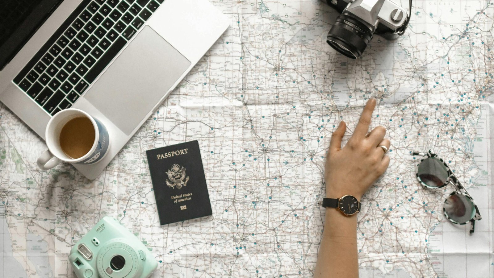 pexels-photo-1051075-1051075 Hand on map with camera, passport, laptop, and coffee, perfect for travel planning inspiration.